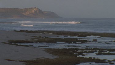 shot across waves breaking in bay land behind