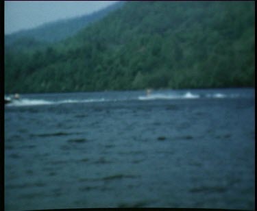 Man on waterskis passes other boys waiting on the pier and falls off