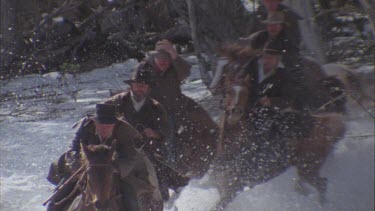 men riding horses over snow covered ground
