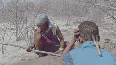 bushman woman and child digging for beetle larvae that make the poison for arrows