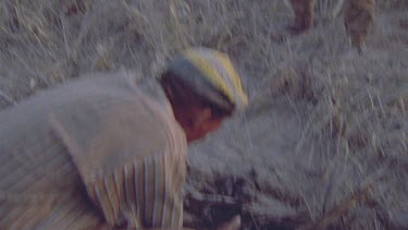 bushmen hunters trying to get warthog out of hole by starting fire