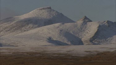 snow capped mountains in tundra landscape.