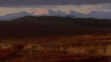 snow capped mountains in tundra landscape, fast moving low cloud