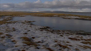 snow capped mountains in tundra landscape, heavy dark cloud above