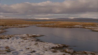 clouds reflected in lake, snow covered foreground