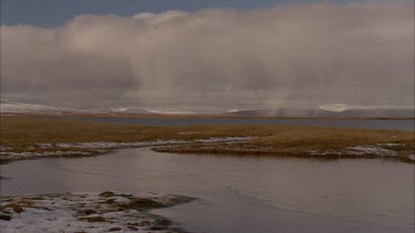 clouds moving over lake, snow covered foreground