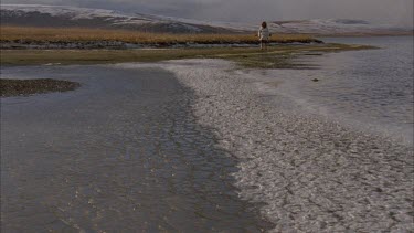 Inuit man walking along frozen edge of the lake