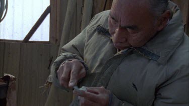 Table with knife or sculpting tools resting on it in the shed hut, Inuit picks each one up and cleans them