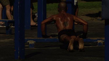 Men doing strength exercises on a pull-up gym at the beach