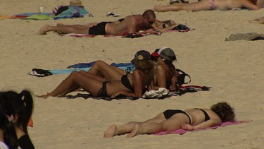 Women in bikinis sunbathing on a beach