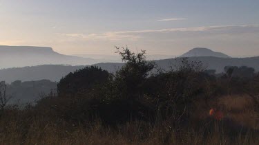 landscape vast distant mountains cliffs dry shrubs grass leaves day