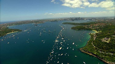 Sydney to Hobart Yacht race. Sydney Harbour. North Head, heading out to sea. City with Harbour Bridge and Opera House in background.