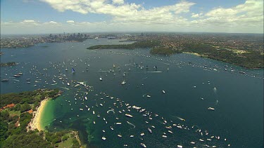 Sydney to Hobart Yacht race. Sydney Harbour. North Head, heading out to sea. City with Harbour Bridge and Opera House in background.