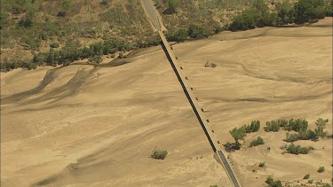 Aerial area around Burketown, Tropical North Queensland. The Gulf Savannah. Far North-western Queensland. Bridge over dry Albert River. Dry Season. As camera gains altitude see cultivated land