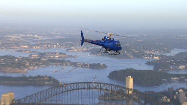 Sydney at sunrise. Helicopter and early morning light.  blue helicopter.  Harbour Bridge, North Sydney flying towards Manly over Lower North Shore suburbs towards Tasman sea, South Head and North Head...