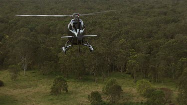 Black Helicopter flies over bushland on outskirts of Sydney. See Neppean river and suburbs in distance.