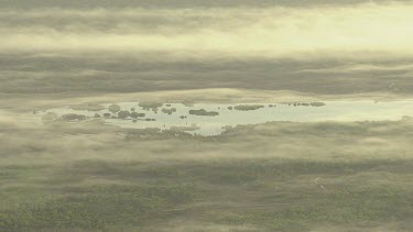 Sunrise from above, clouds over land with trees and billabong water