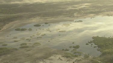 Sunrise from above, clouds over land with trees and billabong water