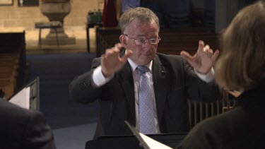 Conductor conducts a choir singing in a church