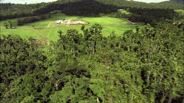 Aerial over rainforest near Mission Beach, Queensland shows that much of the area has been cleared for farming and roads.