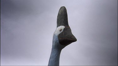 Low angle shot looking up at giant cassowary statue with dark clouds overhead.