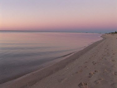Pastel colours adorn the sky as the ocean gently laps an Australian beach