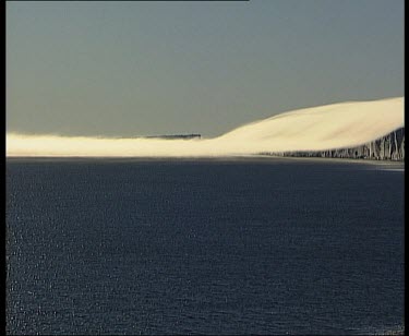 Thick layer of very low cloud over blowing over cliffs and over sea. Looks like tablecloth.