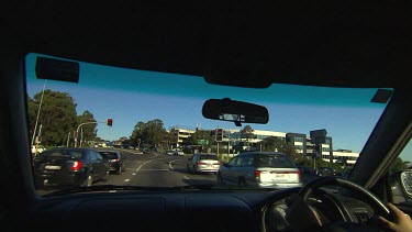 Point of View POV driving in a car, stopped at traffic light.