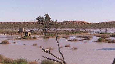 Landscape - flooded desert plain, water tank. Sand Dunes in background.