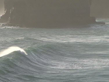 Surf waves rolling in to shore, spray