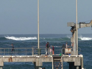 People on pier with waves crashing and ocean
