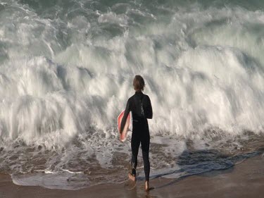 Surfer. One surfer paddling out to sea through waves and spray. Surfing