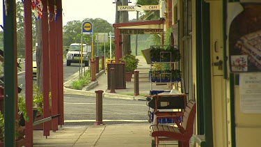 Long shot. Small town with old fashioned shops and shop fronts. Perspective shot down sidewalk pavement.