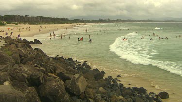 Establishing shot wide shot Main Beach Byron Bay. Surfers and body boarders.