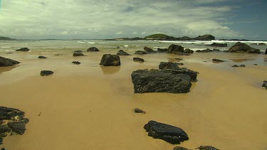 Black rocks on beach, could be volcanic origin.
