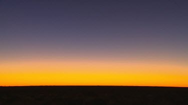 Horizon at sunset. The sky is blue orange yellow, the Earth a flat black horizontal band block of colours