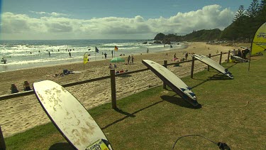 Surfboards drying against a railing. Beach in background.