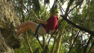 Young woman abseiling down cliff