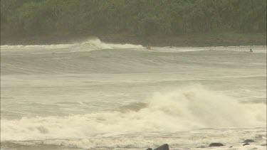 Stormy rough seas with high waves and surfers.