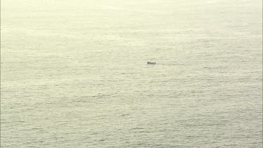 Very Wide shot of fishing boat in centre of still ocean