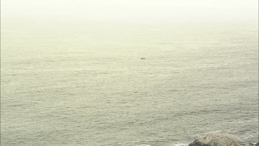 Very Wide shot of fishing boat in centre of still ocean.