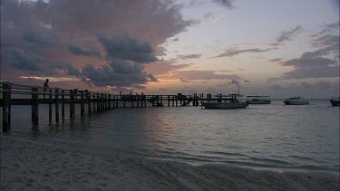 Long shot pier jetty dock sunset and beach, people looking at water