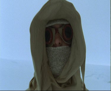 Face of man covered up for survival in extreme cold of Antarctic. He wears goggles, and a balaclava type woolen hat. Only his nose is exposed.
