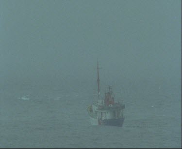 Ship on stormy rough seas. The sky is grey it is snowing or raining.