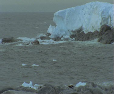 Edge of ice sheet or ice shelf. Men in zodiac inflatable dinghy heading through bay for beach