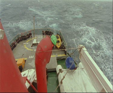 Stern or back of ship moving through rain and stormy seas.