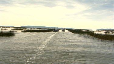 Motor boats moving through the reeds on Lake Titicaca