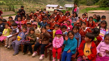 A group of school kids gathered outside, waving