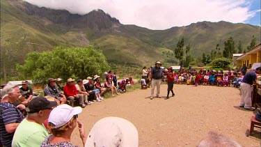 A group of school kids gathered outside with one doing a presentation for a group of tourists