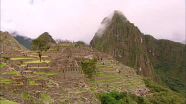 Machu Picchu panning side on view with a few clouds over the mountains